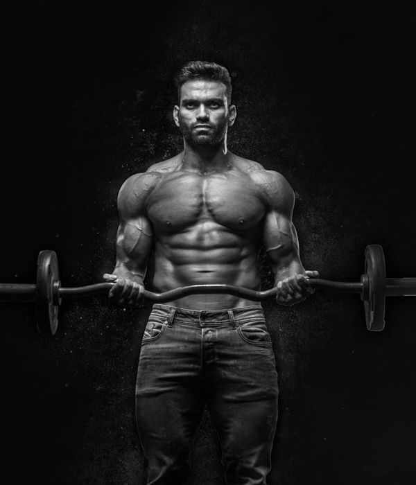 Man performing a powerful strength pose in a dimly lit environment.